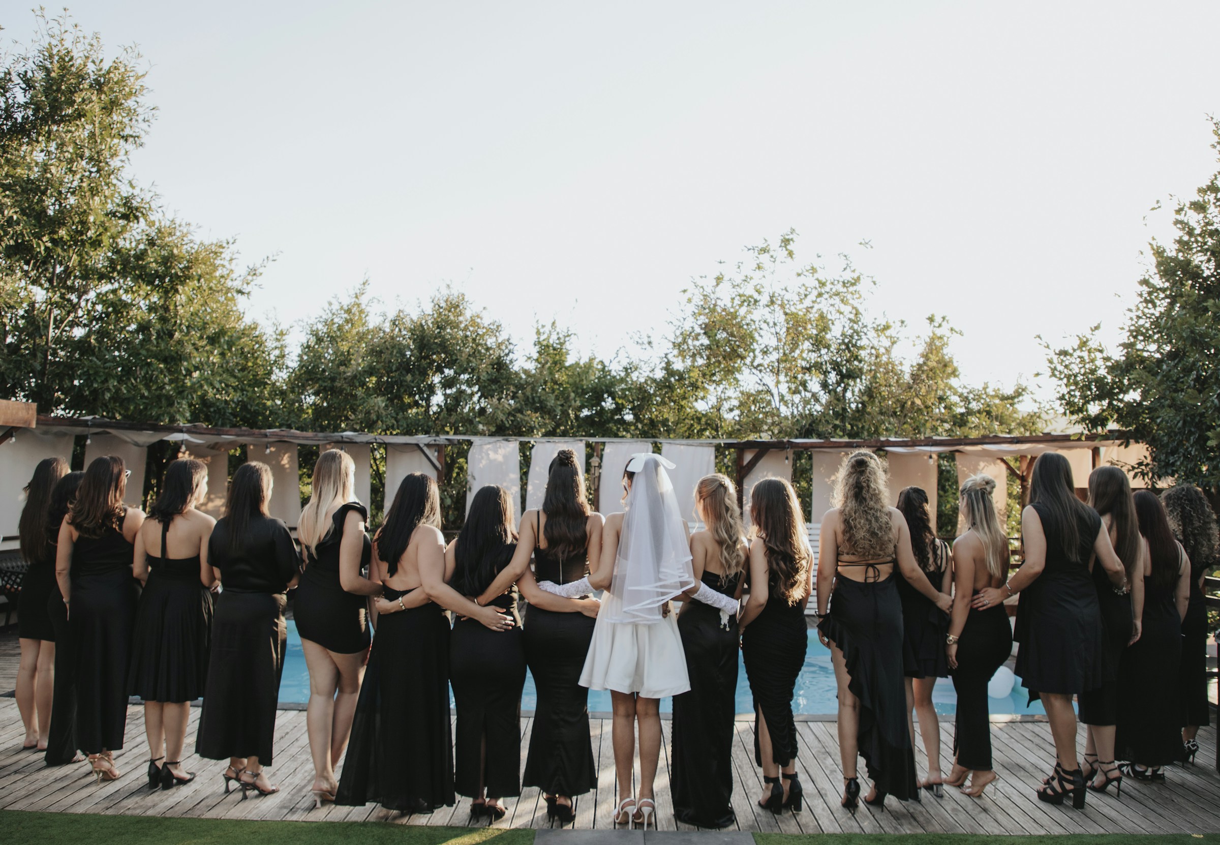 A group of women in black dresses gathered by a pool