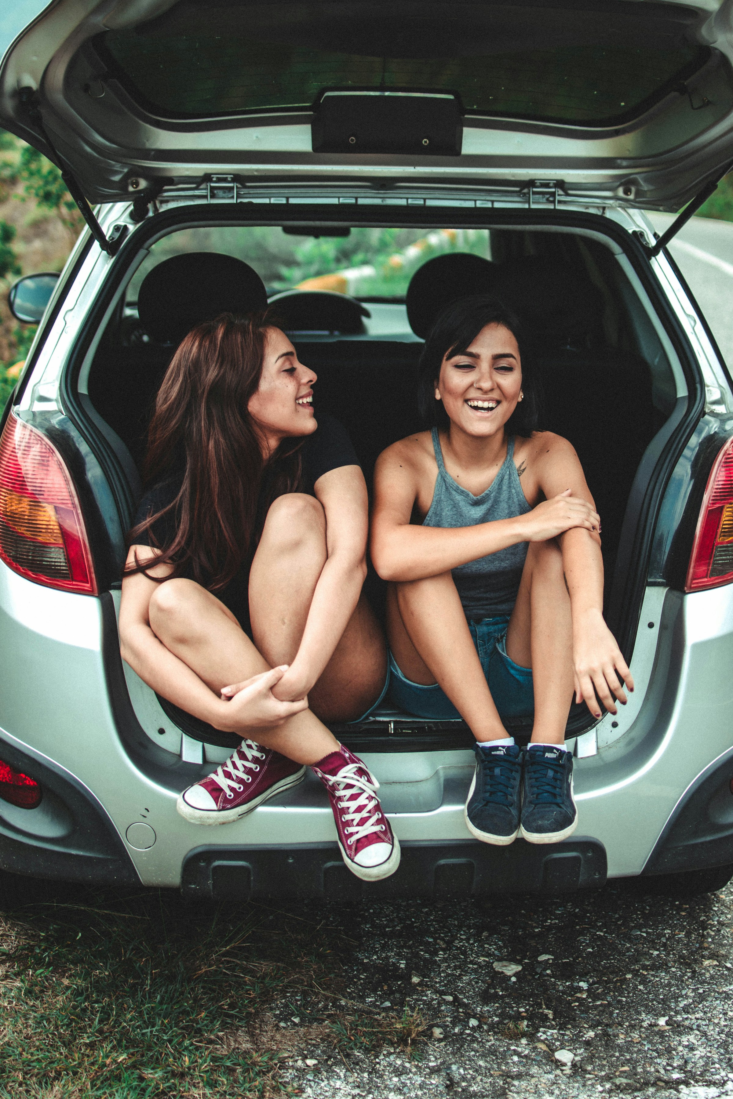 Two women laughing together in the back of a car